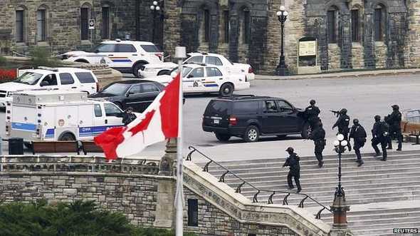 Grupos de policía armada se ven el los alrededores del edificio central del Parlamento en Ottawa.