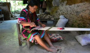 Artesana de la comunidad Tlacoatzintepec tejiendo un huipil.