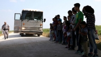 Inmigrantes se entregan a los agentes de la patrulla fronteriza después de cruzar ilegalmente la frontera de México a Estados Unidos y esperan ser transportados para su procesamiento en el sector del Valle del Río Grande, cerca de McAllen, Texas, 2 de abril de 2018