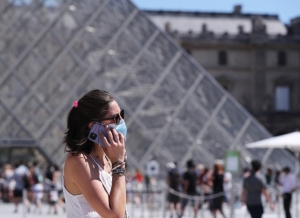 Una mujer con cubrebocas frente a la Pirámide del Museo del Louvre, en París.