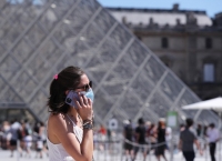 Una mujer con cubrebocas frente a la Pirámide del Museo del Louvre, en París.