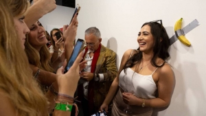 Una visitante es fotografiada frente a la obra &#039;Comediante&#039;, el sábado. En vídeo, el momento en el que un hombre se come el plátano.