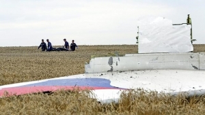 Varias personas transportan un cadáver en medio de los destrozos del vuelo MH17 de Malaysia Airlines