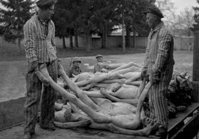 Los soldados estadounidenses, tras la liberación del campo, supervisan a varios prisioneros mientras éstos cargan cadáveres