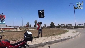 Un combatiente del EI coloca una bandera del grupo en Ramadi