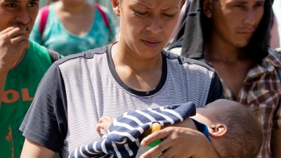 Una mujer con su hijo forma parte de en una caravana de centroamericanos y cubanos que pretende llegar a EE.UU. y marcha por una carretera en Tapachula, estado de Chiapas, México, el 28 de marzo de 2019.
