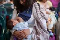 Una mujer amamanta a su hijo en un parque.
