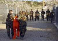 Policía militar de EEUU traslada a un detenido en Camp X-Ray, en la base de Guantánamo, en una imagen de 2002 (Reuters). 