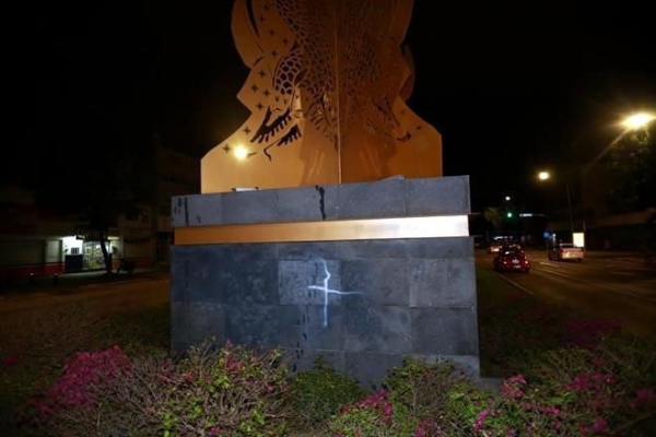 Un hombre que participaba en la marcha, se separó del grupo y con una pintura en aerosol presuntamente vandalizó la base de la escultura.