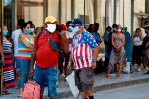 Ciudadanos cubanos hacen fila afuera de un banco.