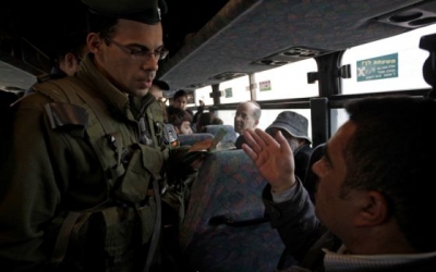 Un soldado israelí pide la documentación a un palestino en un autobús, en el puesto de control de Hizme, antes de entrar en Jerusalén.