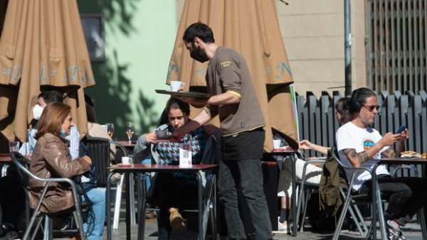 Un camarero sirve a unas clientas en una terraza de un bar de Barcelona 