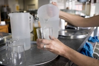 Una mujer echa agua en un vaso.  