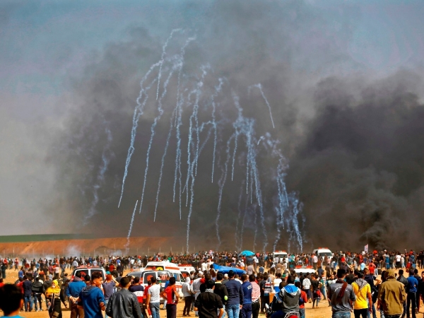 Manifestantes palestinos huyen del gas lacrimógeno lanzado por soldados israelíes durante las protestas en la frontera entre Israel y Gaza. 