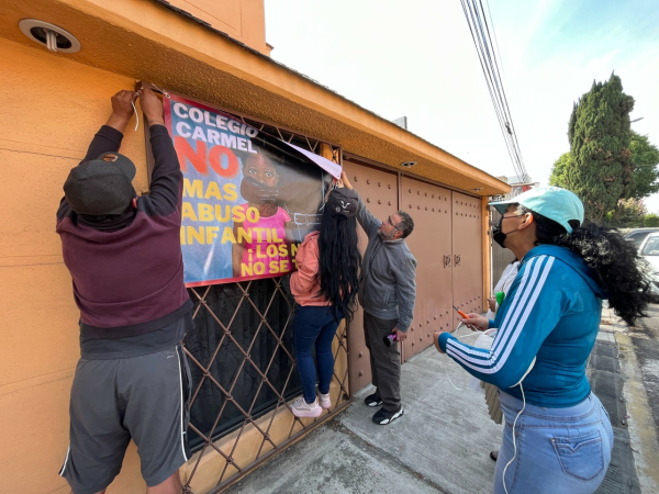 Familiares de una víctima de abuso en el Colegio Carmel, en Coyoacán, al denunciar las agresiones en una manta. Autoridades de la CDMX colocaron ayer sellos de suspensión de actividades en el plantel. 