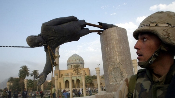 Soldado de la Marina de EE.UU. junto a la estatua del líder iraquí Saddam Hussein en el centro de Bagdad en abril de 2003/