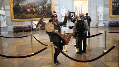 Manifestante carga con el atril de Nancy Pelosi durante el asalto al Capitolio de EE.UU. el 6 de enero de 2021.