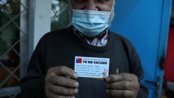 Un hombre sin hogar en Chile muestra su cartilla de vacunación después de ser inoculado