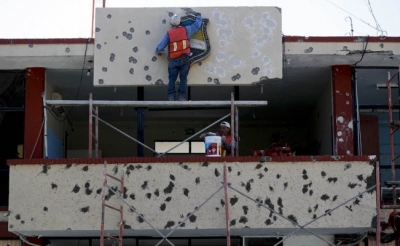 Trabajadores reparando la fachada del ayuntamiento, lleno de agujeros de bala, en Villa Unión, México.