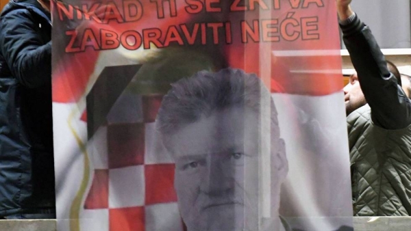 Bosniocroatas sujetan una bandera que muestra a Slobodan Praljak, en Mostar (Bosnia) este miércoles, tras el suicidio del exgeneral.